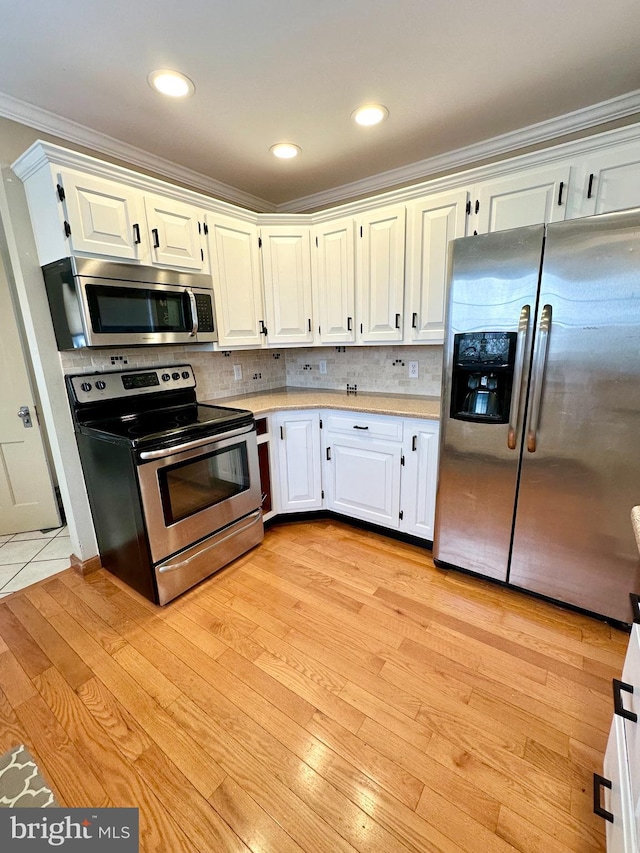 kitchen featuring backsplash, white cabinetry, ornamental molding, and appliances with stainless steel finishes