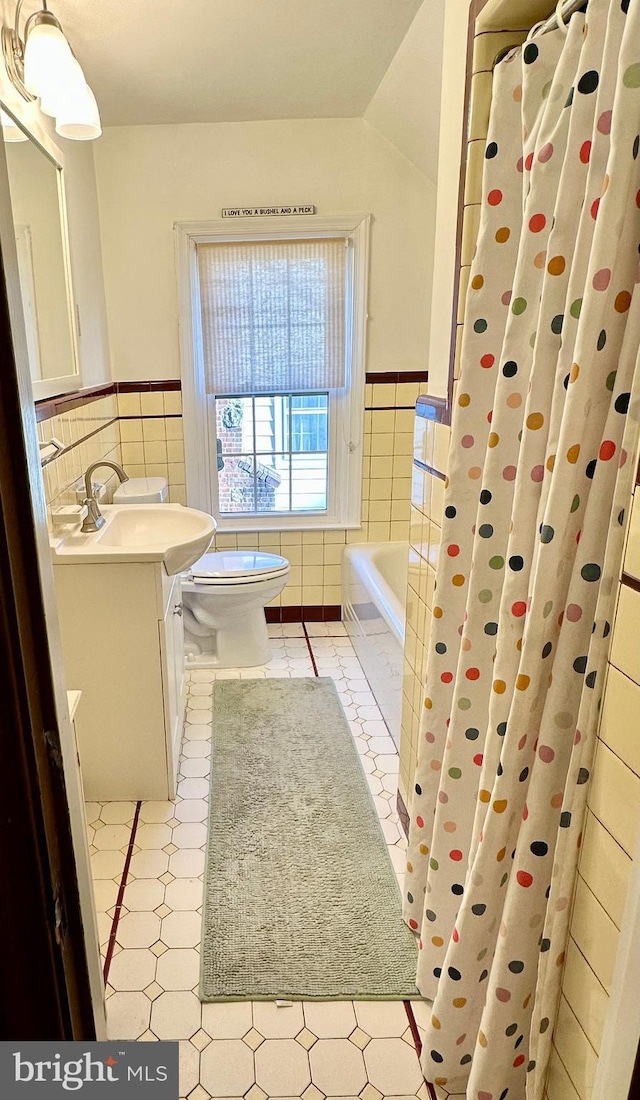 full bathroom with plus walk in shower, tile walls, tile patterned flooring, vanity, and toilet