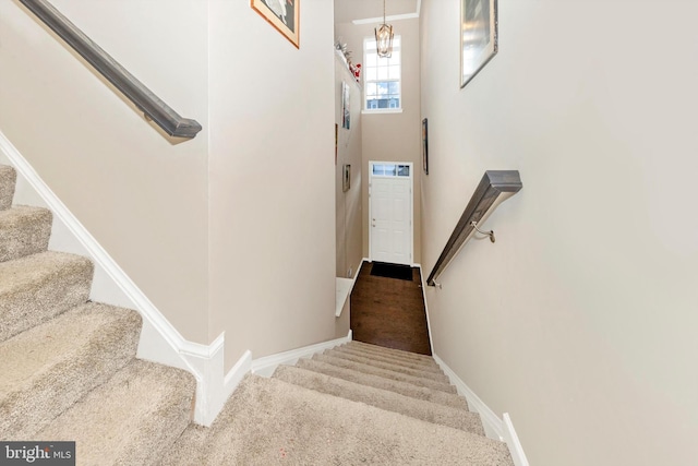 staircase with carpet flooring and a notable chandelier