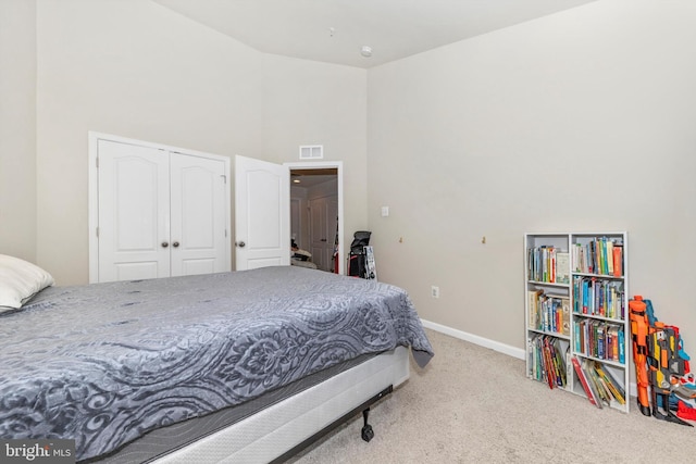 bedroom featuring a closet, light colored carpet, and a high ceiling