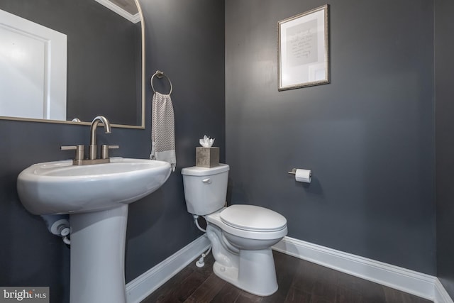 bathroom featuring wood-type flooring, toilet, crown molding, and sink