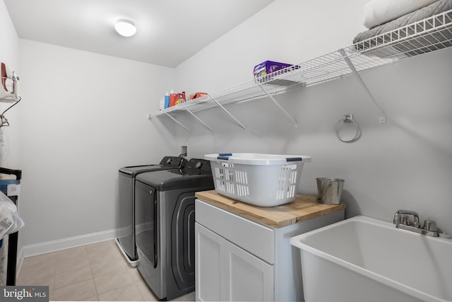 laundry area with cabinets, light tile patterned floors, washing machine and dryer, and sink