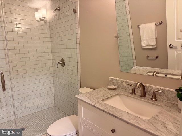 bathroom featuring vanity, toilet, and a shower with shower door