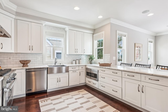 kitchen featuring white cabinets, sink, appliances with stainless steel finishes, tasteful backsplash, and a kitchen bar