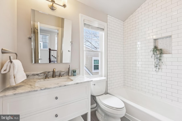 full bathroom with tiled shower / bath, vanity, lofted ceiling, and toilet