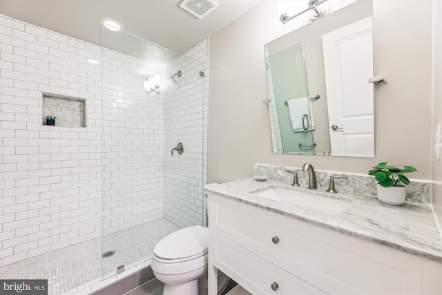 bathroom with a tile shower, vanity, and toilet