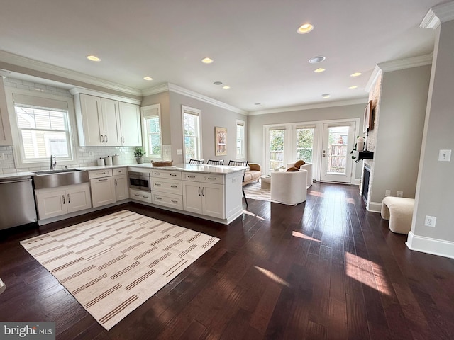 kitchen featuring dishwasher, sink, backsplash, kitchen peninsula, and white cabinets