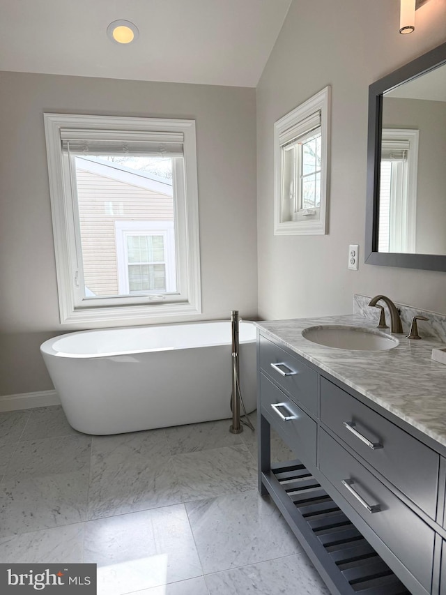 bathroom featuring a bathtub, vanity, and vaulted ceiling