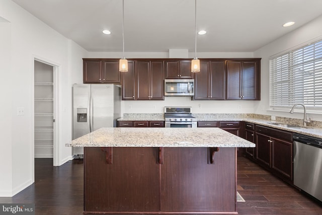 kitchen featuring sink, a kitchen island, decorative light fixtures, and appliances with stainless steel finishes