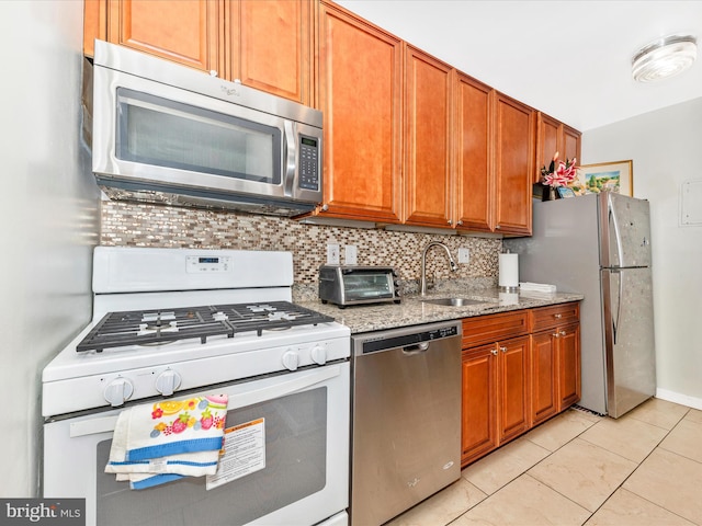 kitchen featuring light stone countertops, appliances with stainless steel finishes, backsplash, sink, and light tile patterned floors