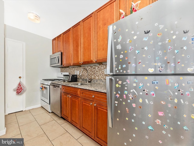 kitchen featuring sink, tasteful backsplash, light stone counters, light tile patterned floors, and appliances with stainless steel finishes