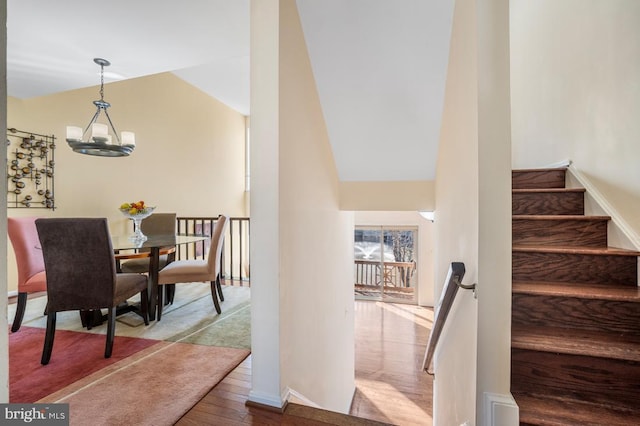 dining area featuring wood finished floors, vaulted ceiling, baseboards, and an inviting chandelier