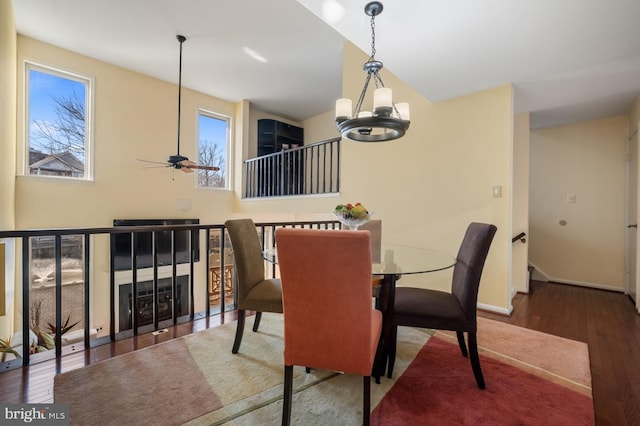 dining room with ceiling fan with notable chandelier, wood finished floors, and baseboards