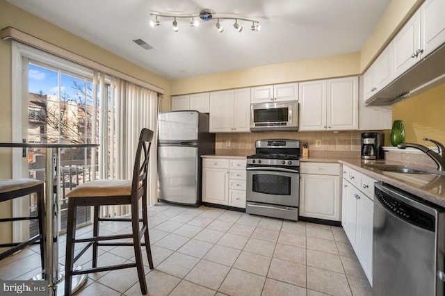 kitchen featuring stainless steel appliances, visible vents, decorative backsplash, white cabinetry, and a sink