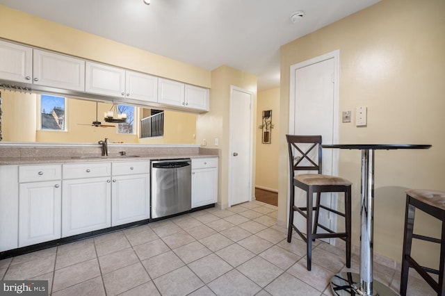 kitchen featuring light countertops, stainless steel dishwasher, a sink, and white cabinetry