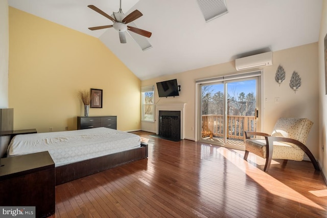 bedroom with visible vents, a wall unit AC, a fireplace with flush hearth, hardwood / wood-style floors, and access to outside