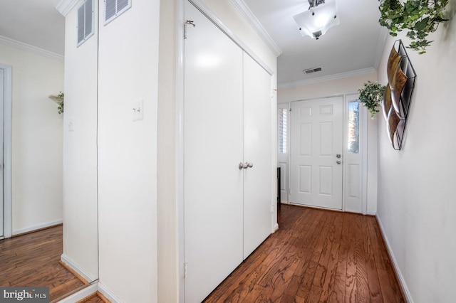 corridor featuring visible vents, crown molding, and wood finished floors