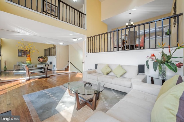 living area featuring stairs, a high ceiling, an inviting chandelier, and wood finished floors