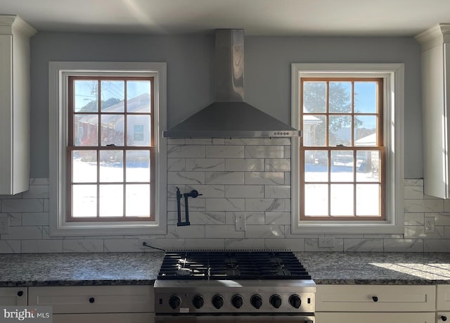 kitchen featuring white cabinets, decorative backsplash, stainless steel range, and wall chimney exhaust hood