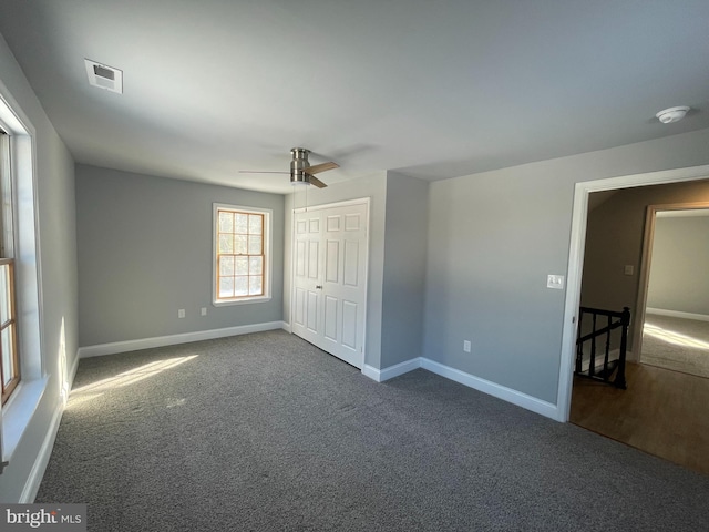 unfurnished bedroom featuring ceiling fan, a closet, and dark colored carpet