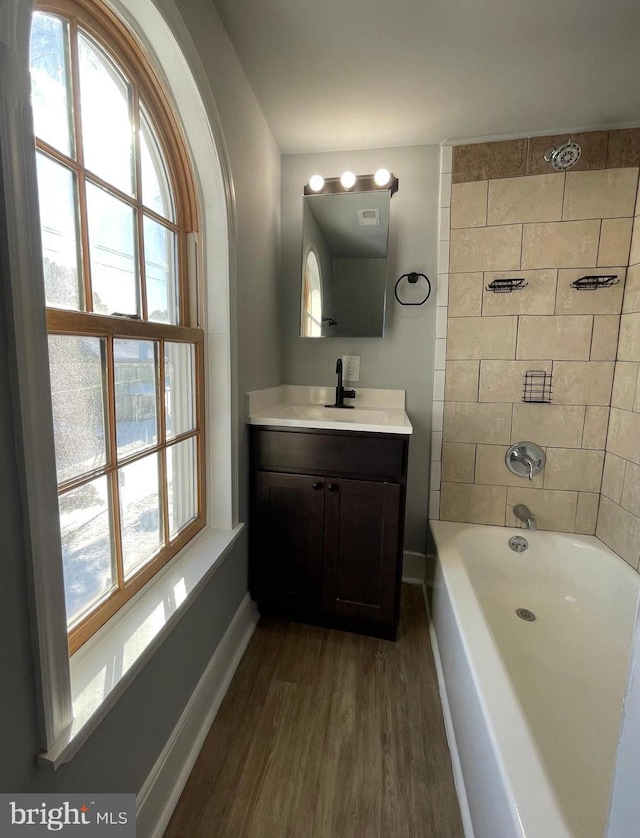 bathroom with tiled shower / bath, plenty of natural light, vanity, and hardwood / wood-style flooring