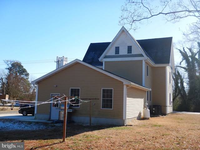 rear view of house with central AC unit and a yard