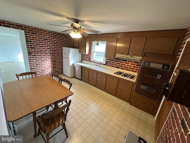 kitchen with ceiling fan, sink, brick wall, and white appliances