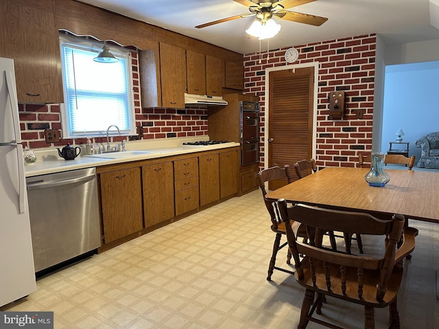 kitchen with ceiling fan, sink, brick wall, and white appliances