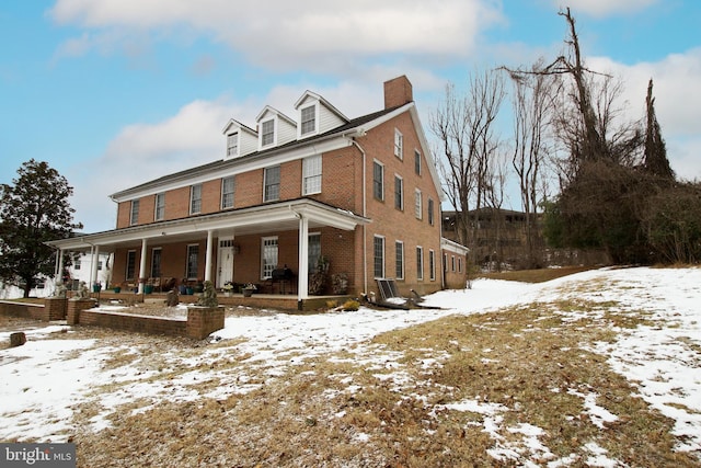 snow covered back of property with a porch