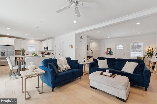 living room with light hardwood / wood-style floors, crown molding, and ceiling fan