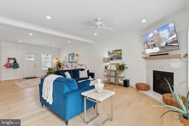 living room with beamed ceiling, a fireplace, hardwood / wood-style flooring, ceiling fan, and crown molding