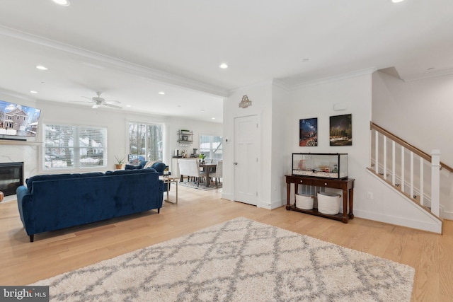 living room featuring light wood-type flooring, ceiling fan, and crown molding