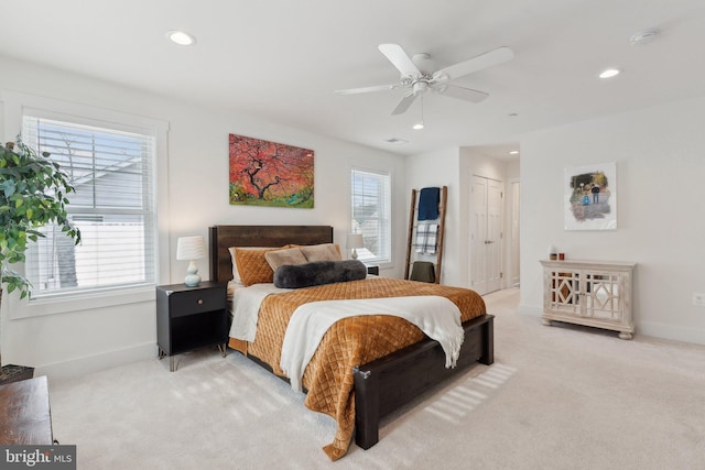 bedroom with ceiling fan, light colored carpet, and a closet