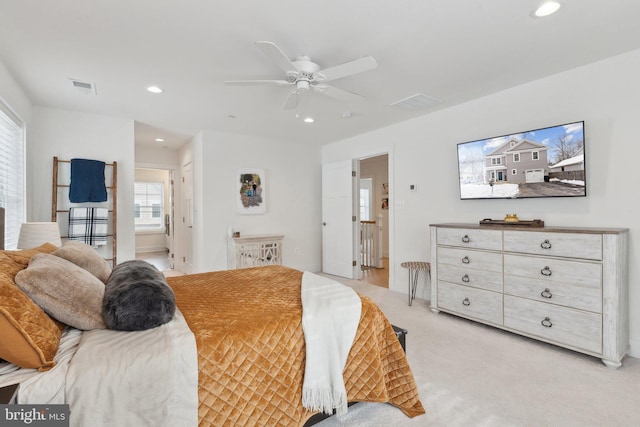 bedroom featuring ensuite bathroom, ceiling fan, light carpet, and multiple windows