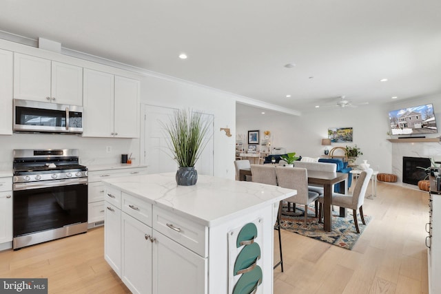 kitchen featuring white cabinetry, appliances with stainless steel finishes, a premium fireplace, and a kitchen island