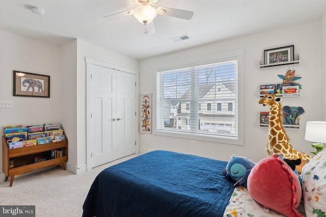 bedroom with light carpet, ceiling fan, and a closet