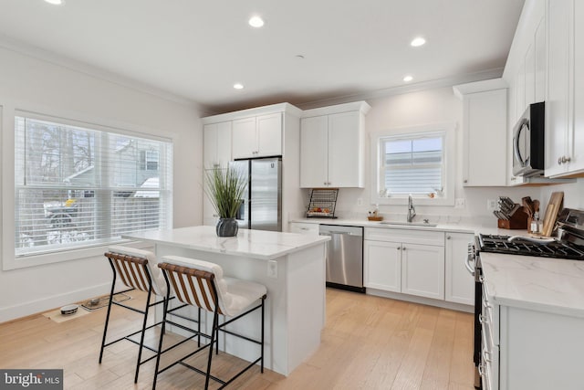 kitchen with appliances with stainless steel finishes, sink, white cabinetry, and a center island