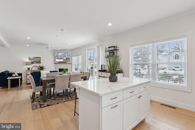 kitchen featuring light hardwood / wood-style floors, light stone counters, white cabinetry, and a kitchen island