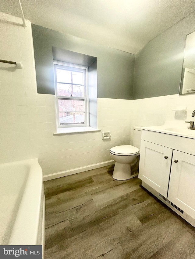 bathroom with a tub to relax in, hardwood / wood-style floors, vanity, and toilet