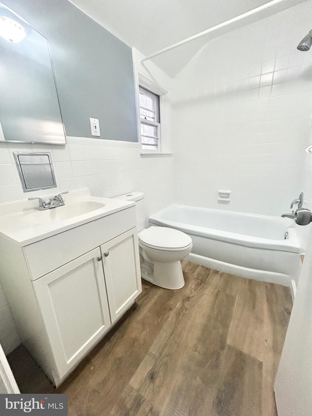 full bathroom with tile walls, toilet, vanity, bathtub / shower combination, and hardwood / wood-style flooring