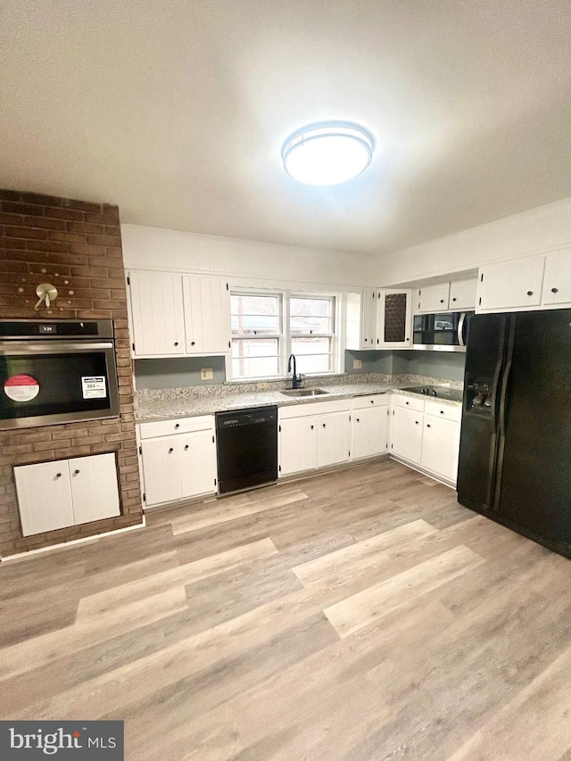 kitchen with sink, light hardwood / wood-style floors, white cabinetry, and black appliances