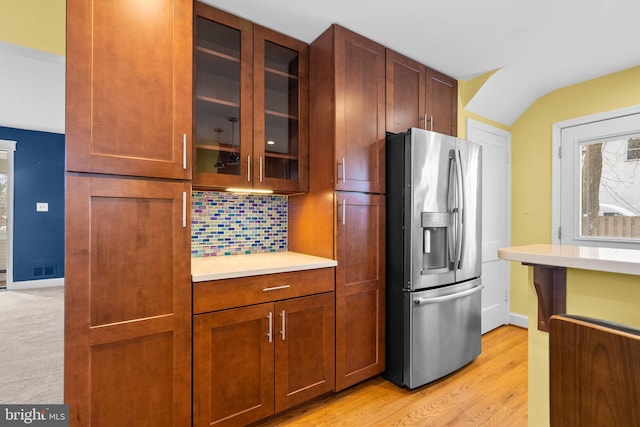 kitchen featuring stainless steel refrigerator with ice dispenser, decorative backsplash, and light hardwood / wood-style flooring