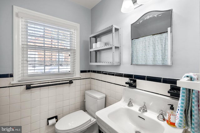 bathroom with sink, toilet, a healthy amount of sunlight, and tile walls