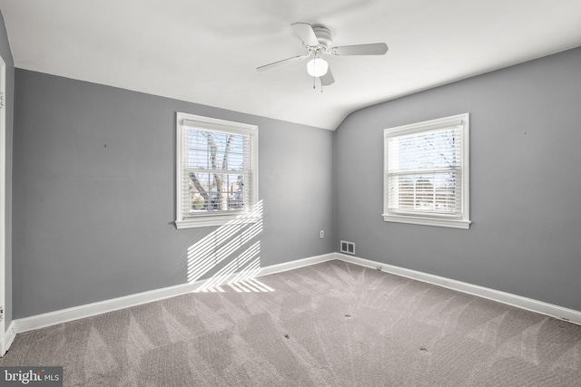 spare room featuring plenty of natural light, carpet floors, vaulted ceiling, and ceiling fan