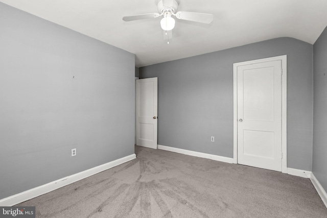 unfurnished bedroom with ceiling fan, vaulted ceiling, and light carpet