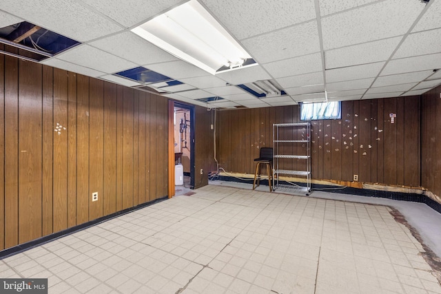 basement with wood walls and a paneled ceiling