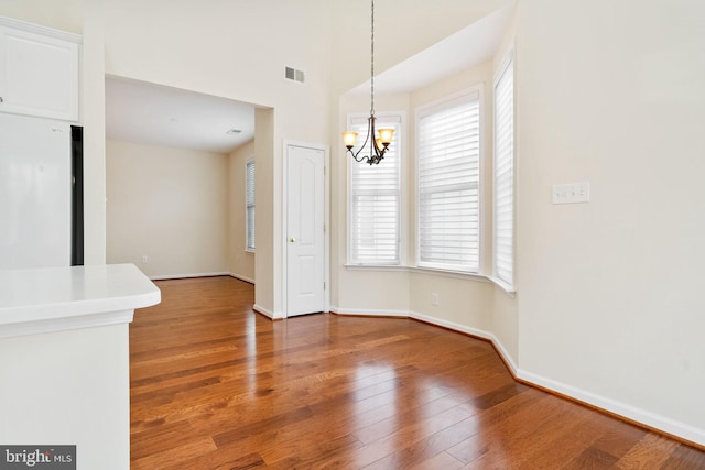 unfurnished dining area featuring a notable chandelier and dark hardwood / wood-style flooring