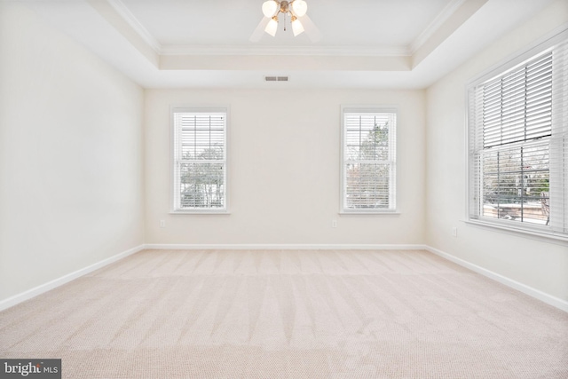 spare room with a raised ceiling, crown molding, light carpet, and ceiling fan