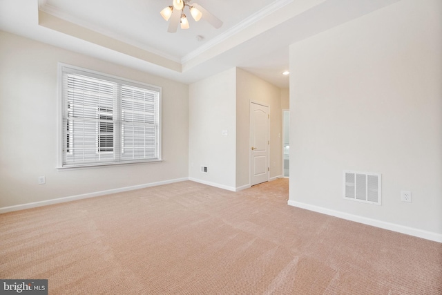 spare room featuring light carpet, a tray ceiling, ornamental molding, and ceiling fan