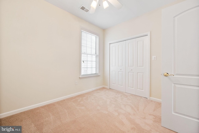 unfurnished bedroom with light colored carpet, ceiling fan, and a closet